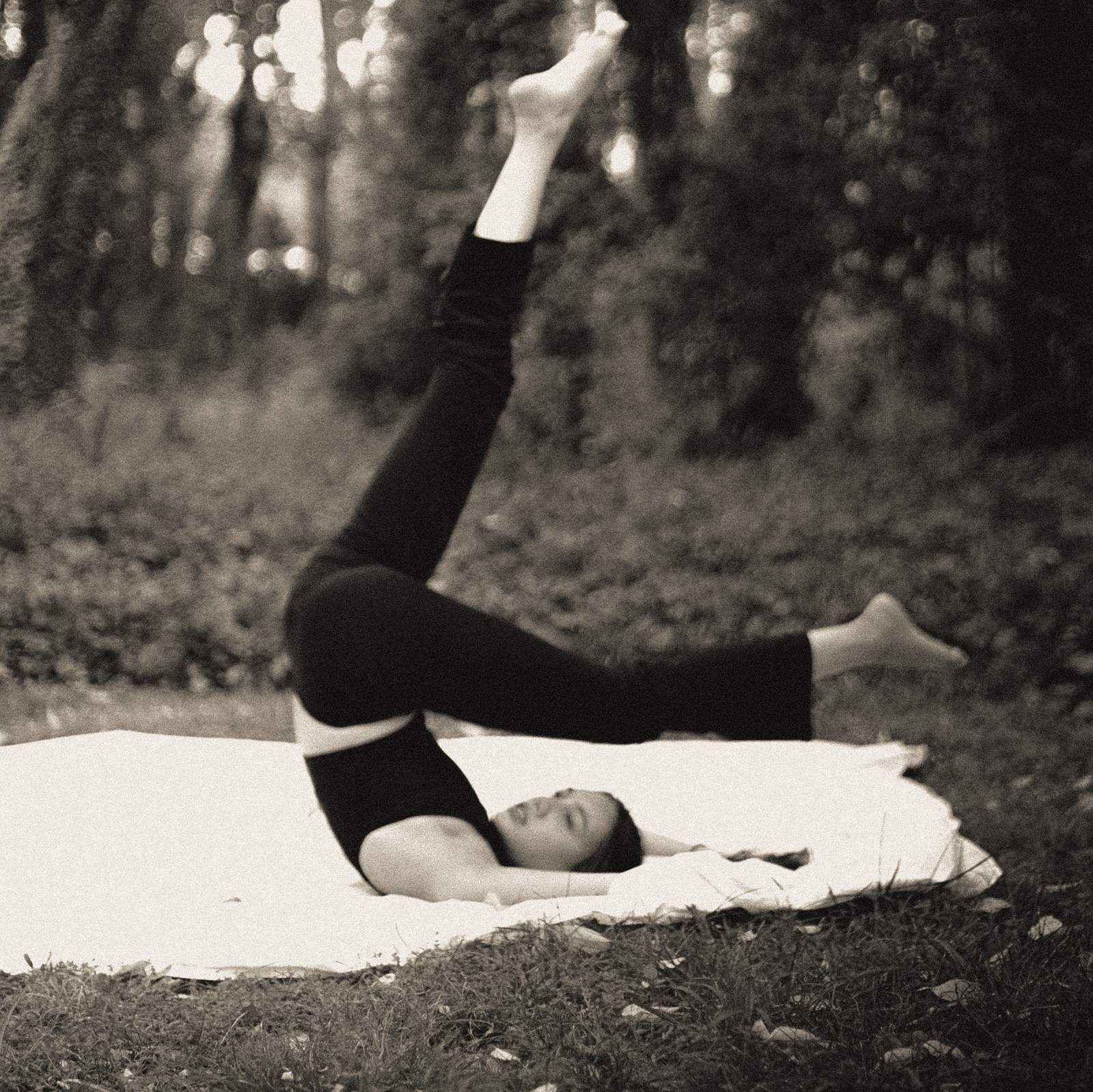 Emilia Méndez recostada sobre una manta en un bosque, con las piernas elevadas; fotografía en blanco y negro con grano