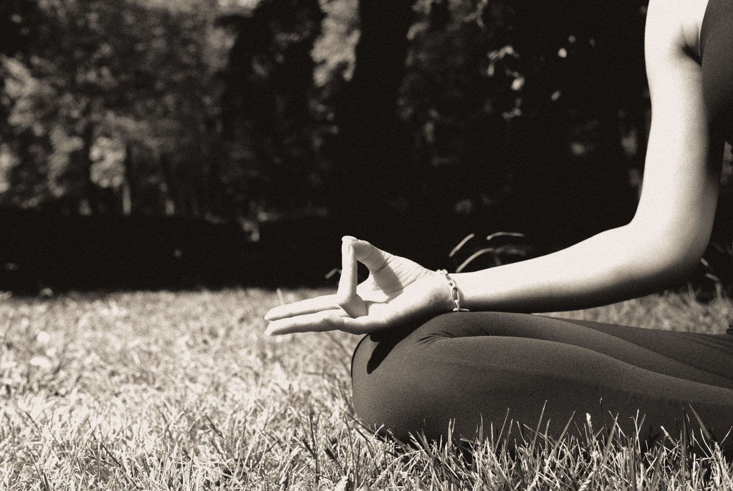 Manos juntas formando un mudra sobre fondo negro; fotografía en blanco y negro